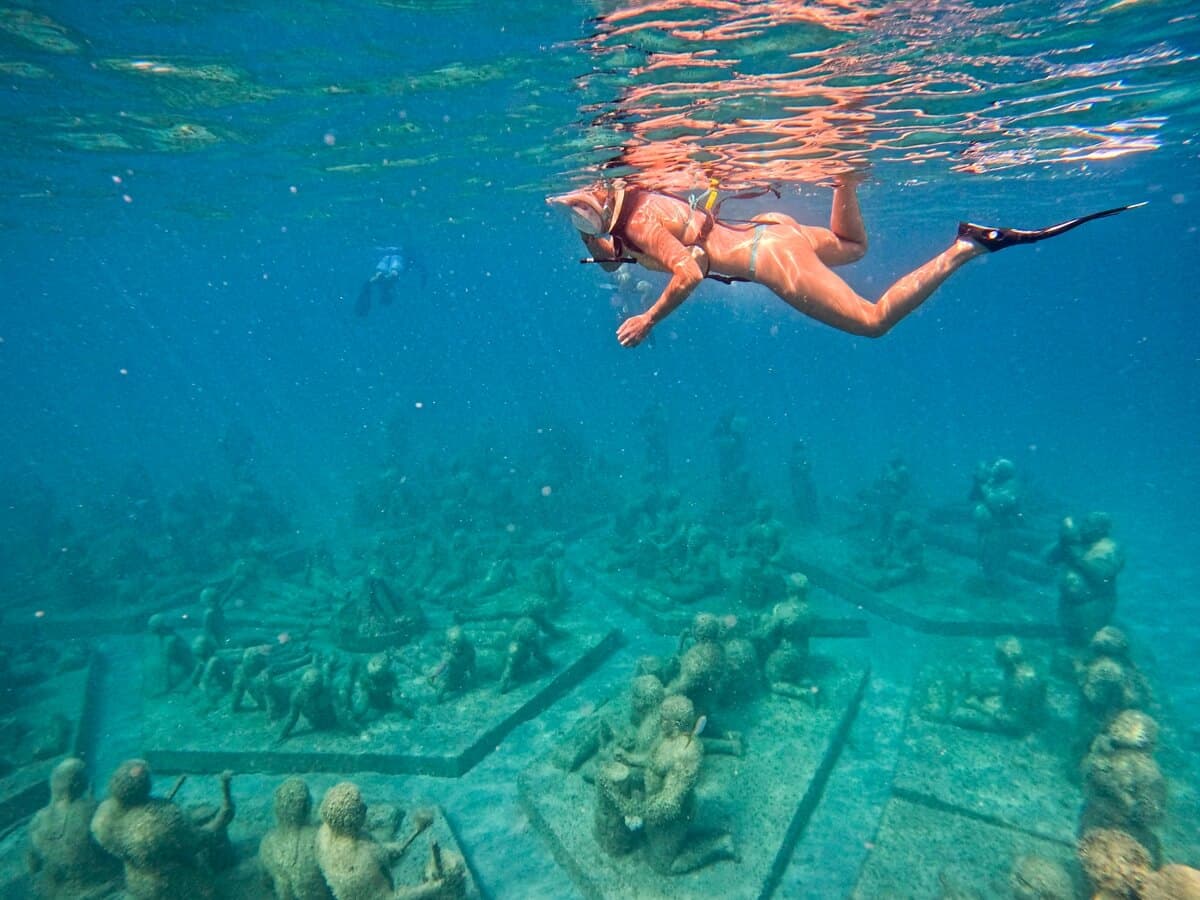 Snorkeler in front of underwater artificial reef sculptures
